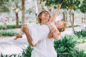 Grandmother carrying gleeful granddaughter in her arms.
