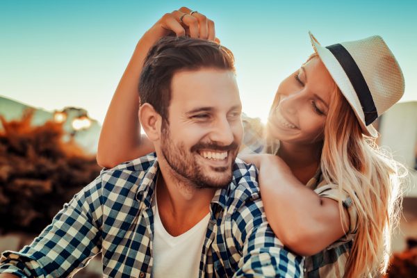 young couple smiling outdoors on a sunny day