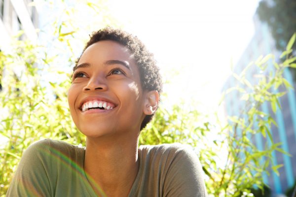 young woman smiling outdoors on a sunny day